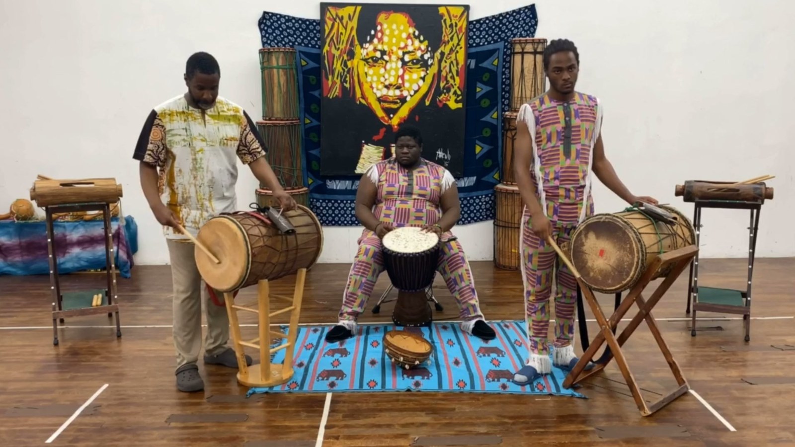 Mahiri and two adult students playing dunun and djembe together in the studio
