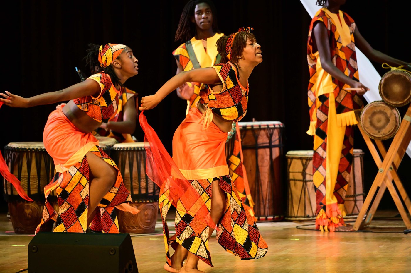 Dancers mid-motion with flowing orange fabric at Birthright