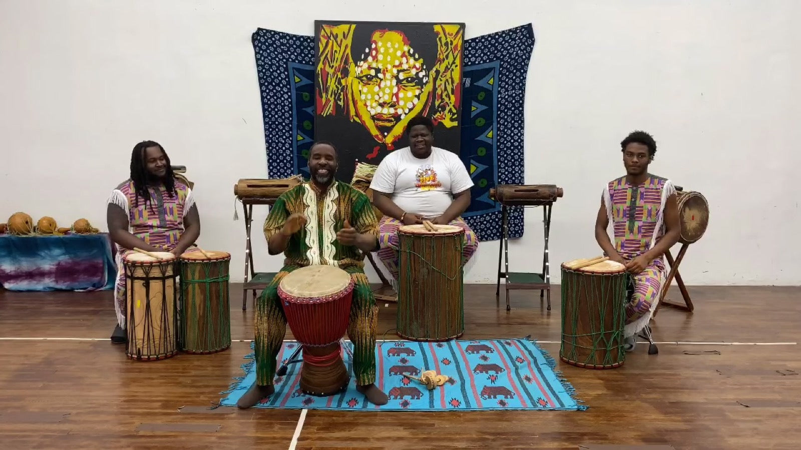 Adult students drumming together in the studio, smiling mid-class