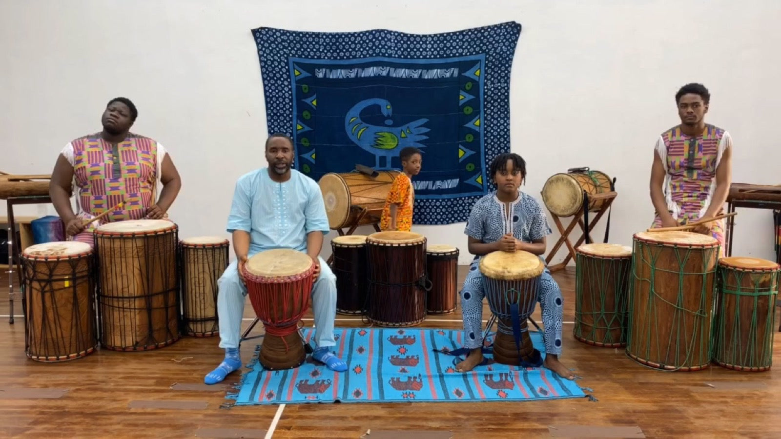 Children and a teen drumming alongside an instructor in the youth class